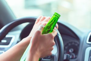 Person holds beer bottle while driving