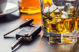Car keys and glass of alcohol on table in pub or restaurant.