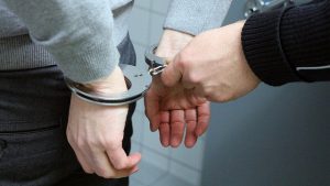 a person's hands behind their back being put in handcuffs