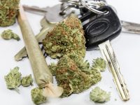 a set of car keys with a joint and marijuana buds sitting around